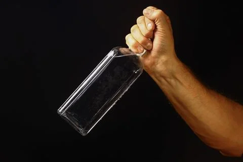 Hand lifting a clear bottle in sharp light Stock Photos