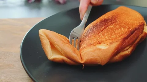 Hand lifting a fluffy golden omelette with fork on dark plate indoors Stock-Footage 342886802
