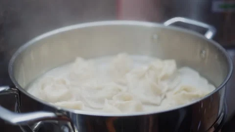 Hand lifting lid off steaming pot of dumplings Stock-Footage 323097712