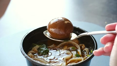Hand lifting a marinated egg from ramen soup Stock Footage 337549384