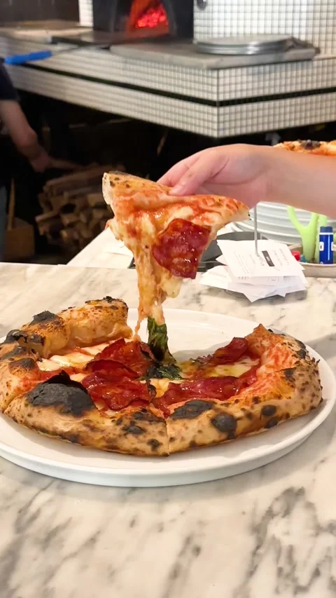 Hand Lifting Salami Pizza Slice with Melting Cheese in Restaurant Stock Footage 339119500