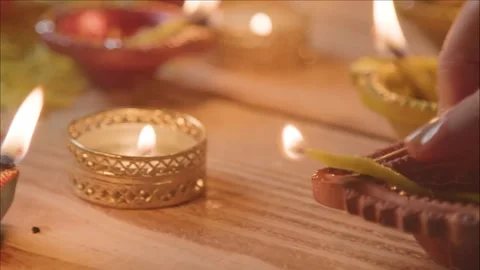 Hand light diya with flame on table at night for warm diwali festival Vídeos de archivo 343887784