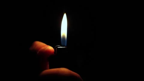 In hand a lighter with fire on a dark background Video stock 229429309