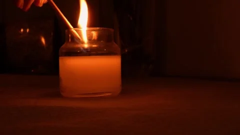 Hand lighting a candle with a match, warm wellness atmosphere Vídeos de archivo 332997770