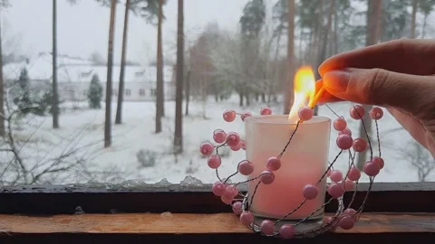 Hand lighting candle with pink beads on wooden windowsill Stock Footage 323112371