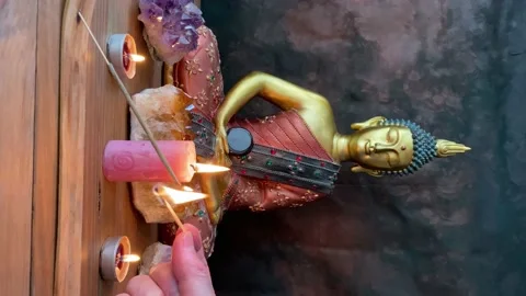 Hand lighting an incense stick with a match on a Buddhist altar. Stock Footage 225878625