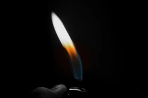 A hand lighting up a lighter on a black background Foto stock