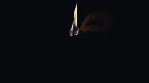 Hand Lighting Thin Black Candle with Match in Dark Room Stock Footage 335884144