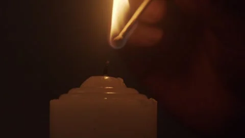 Hand Lighting White Candle with Match Against Dark Background 库存影片 334643818