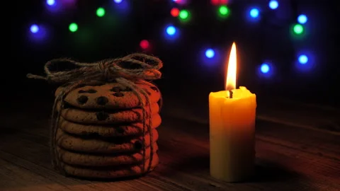 Hand lights a candle against the background of Christmas lights and a stack of Stock Footage 166539527