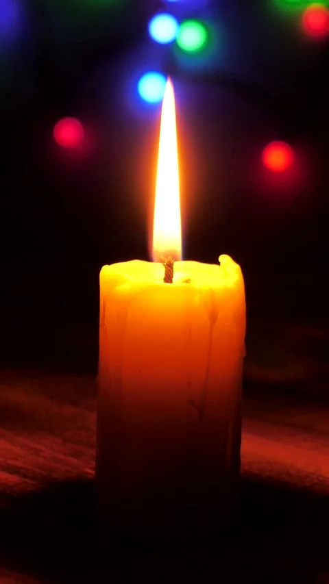Hand lights a candle on the background of Christmas Lights. A candle burns in Stock Footage 305208638