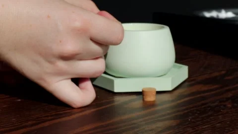 A hand lights a candle in ceramic holder placed on a hexagon gypsum stand next Stock Footage 310337652