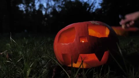 A hand lights a fire inside a Halloween pumpkin and covers it with a hat Video stock 253311383