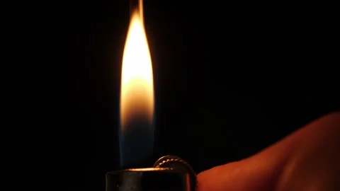 A hand lights a lighter on a dark background. The flame appears in the dark. Stock Footage 228828024