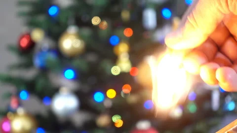 Hand lights a match a background of blurry Christmas lights in 4K Stock Footage 137306359