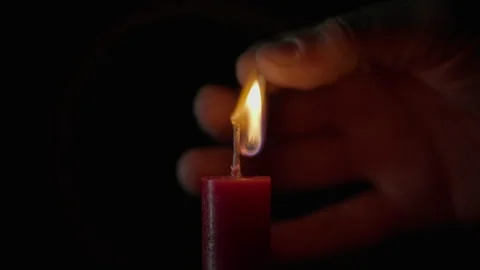 Hand lights paraffin candle using match black background closeup. Bright flame Stock Footage 332501816