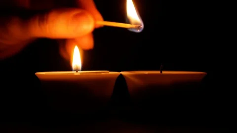 Hand lights a second candle with a match in the dark. Stock Footage 122767854