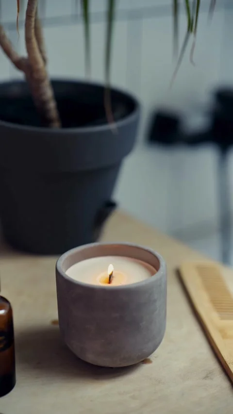 Hand lights white candle in grey concrete jar match Video stock 331774794