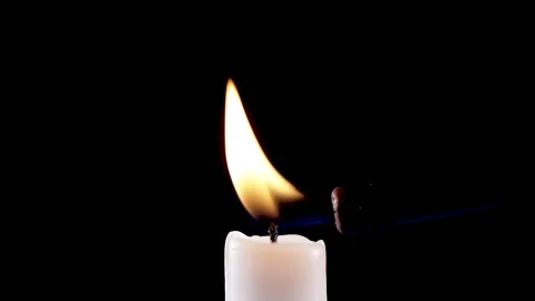 Hand lights a white candle with lighter isolated on a black background. slow mot Video stock 220214820