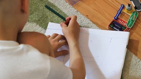 The hand of a little boy draws on a sheet of paper. Stock Footage 112655767