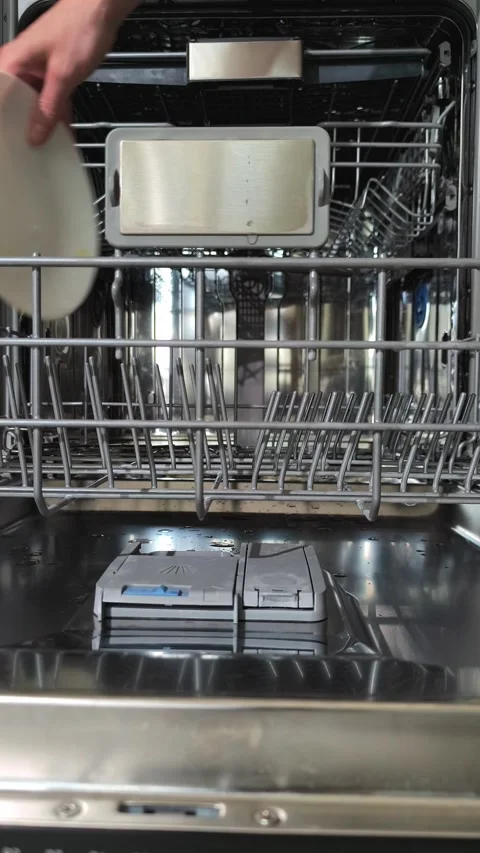 Hand loading dirty dishes into open dishwasher rack before closing door. Pe.. Stock Footage 344889408
