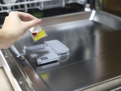Hand Loading A Dishwasher Detergent Pod Stock Photos