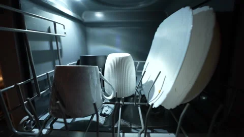 Hand loading mug and plates into modern dishwasher under warm kitchen lighting. Vídeos de archivo 326059891