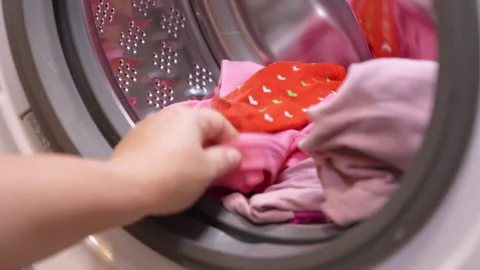 Hand loading pink laundry into washing machine Video stock 322556551