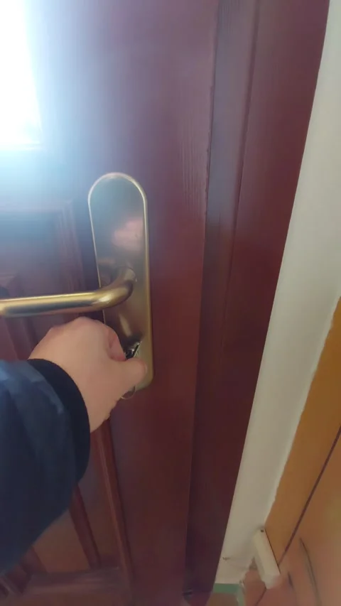Hand Locking or Unlocking a Modern Brown Door with Key and Metal Handle Stock Footage 333641304