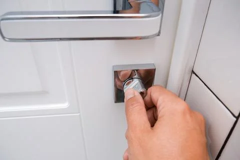 Hand locking a white door using a knob for safety and privacy, home security Stock Photos