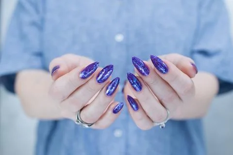 Hand with long nails and a blue and purple color nail polish Stock Photos