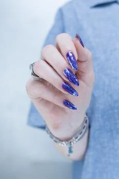 Hand with long nails and a blue and purple color nail polish 库存照片
