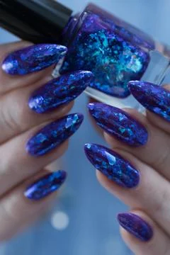 Hand with long nails and a blue and purple color nail polish Photos