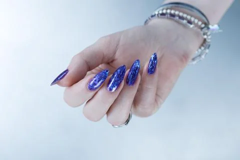 Hand with long nails and a blue and purple color nail polish 库存照片