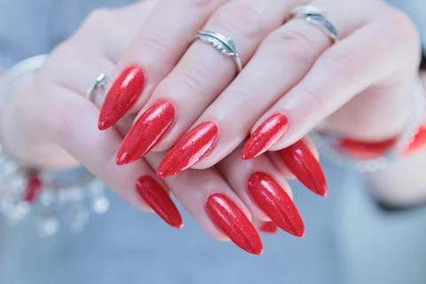 Hand with long nails and a bottle of bright red nail polish Stockfoto's