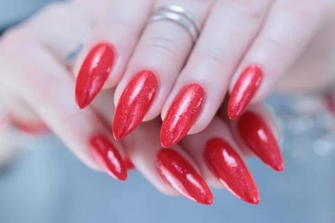 Hand with long nails and a bottle of bright red nail polish Stock-Fotos
