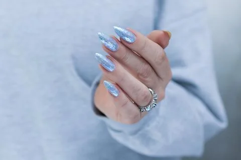 Hand with long nails and bright light blue and silver manicure Stock Photos