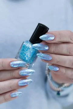 Hand with long nails and bright light blue and silver manicure 库存照片