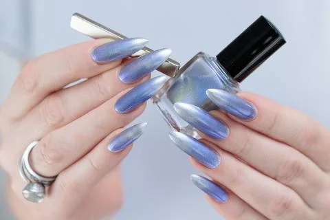 Hand with long nails and bright light blue and silver manicure 스톡 사진