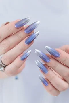 Hand with long nails and bright light blue and silver manicure Stockfoto's