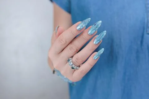 Hand with long nails and bright light blue and silver manicure Stock Photos