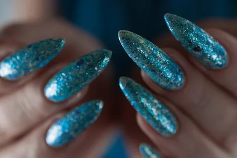 Hand with long nails and bright light blue and silver manicure Stock Photos