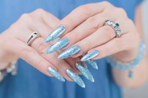 Hand with long nails and bright light blue and silver manicure 库存照片