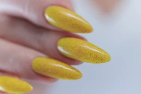 Hand with long nails and a bright yellow orange nail polish Stock Photos