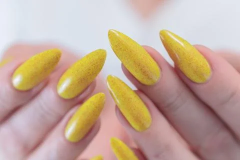 Hand with long nails and a bright yellow manicure 库存照片