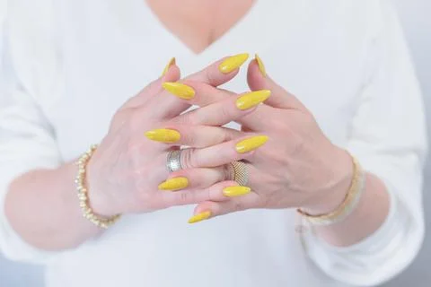 Hand with long nails and a bright yellow manicure Stock Photos