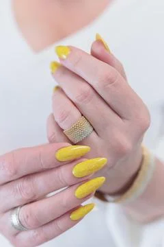 Hand with long nails and a bright yellow manicure Photos