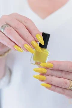 Hand with long nails and a bright yellow orange nail polish Stock-Fotos