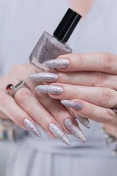 Hand with long nails and a gray silver and red manicure Stock Photos