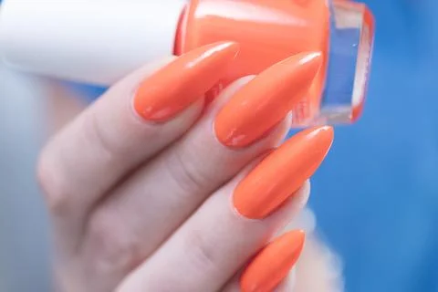 Hand with long nails and light orange coral neon manicure Stock Photos